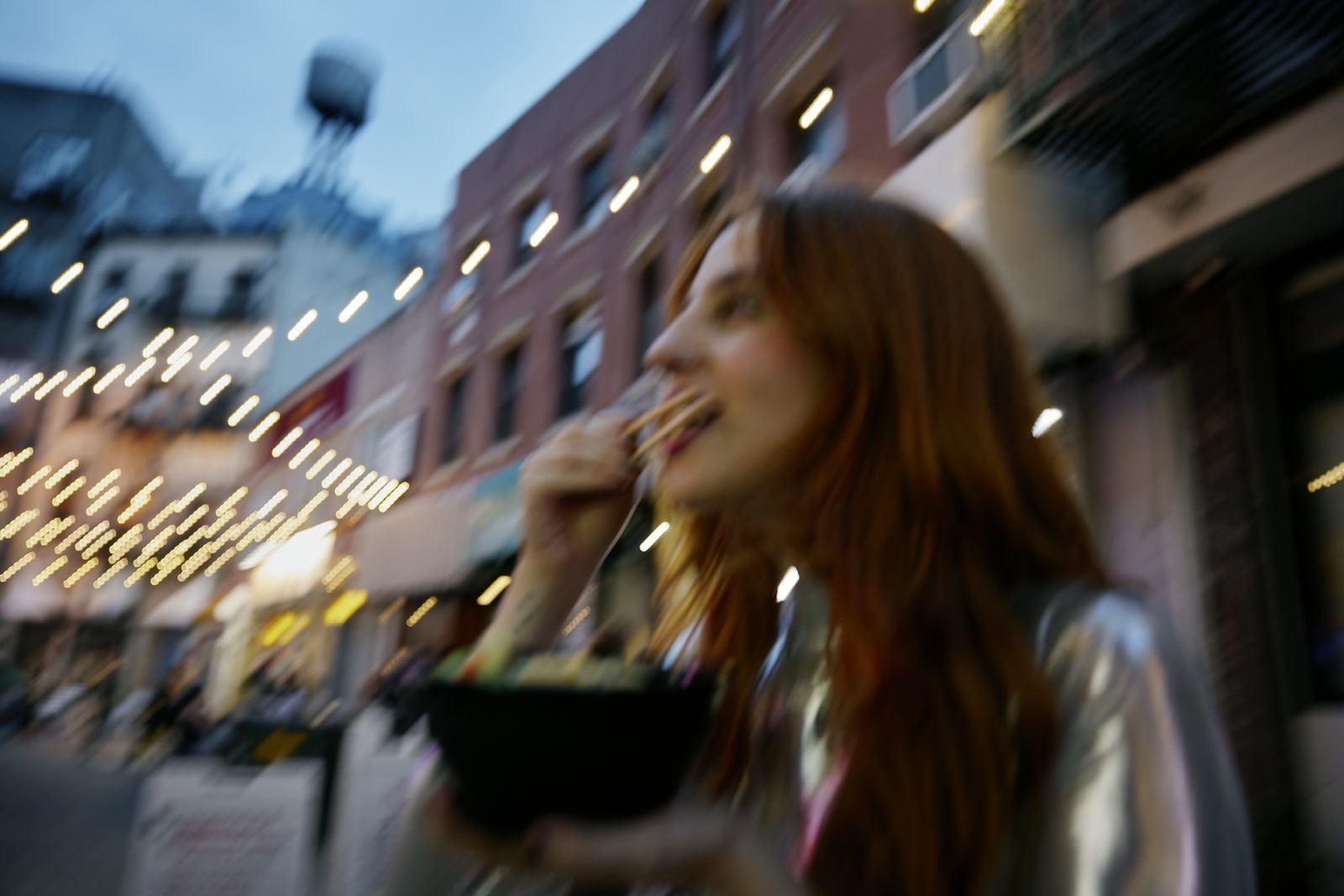 Eating noodles under the bright city lights at night
