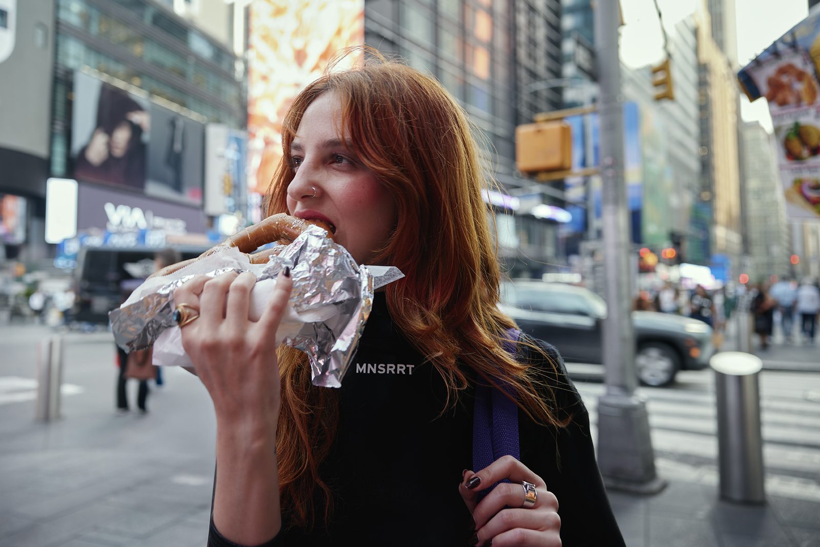 Biting into foil-wrapped street food on a busy sidewalk