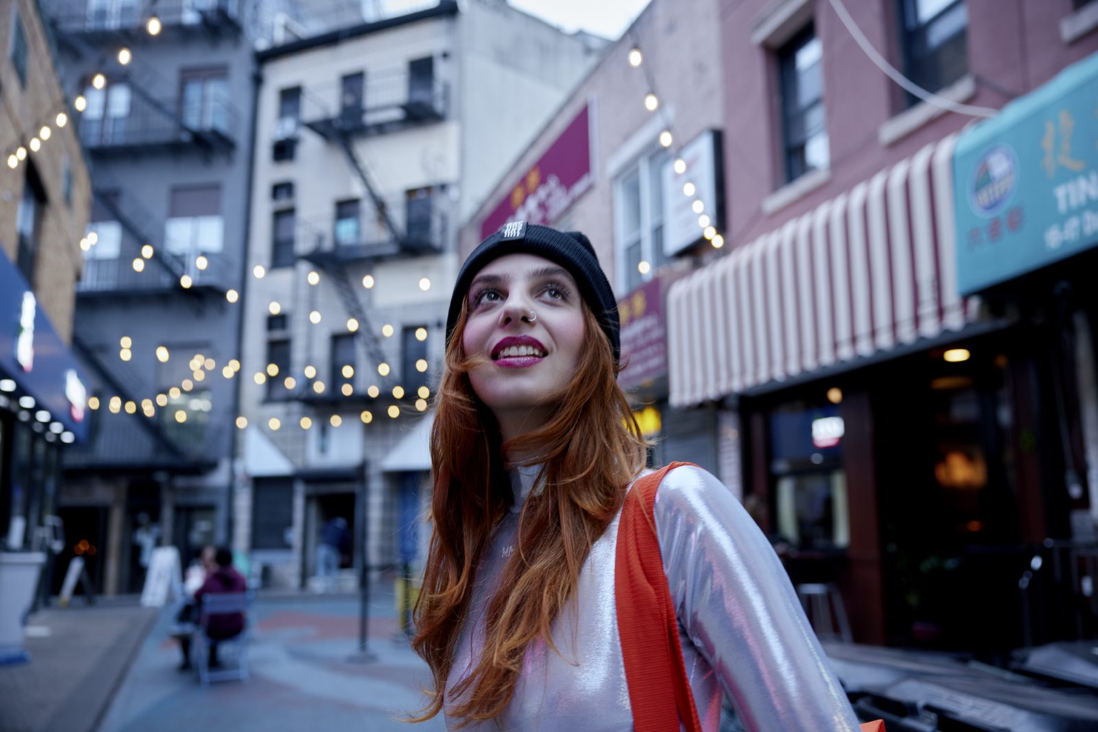 A woman on a fairy-lit downtown street at dusk