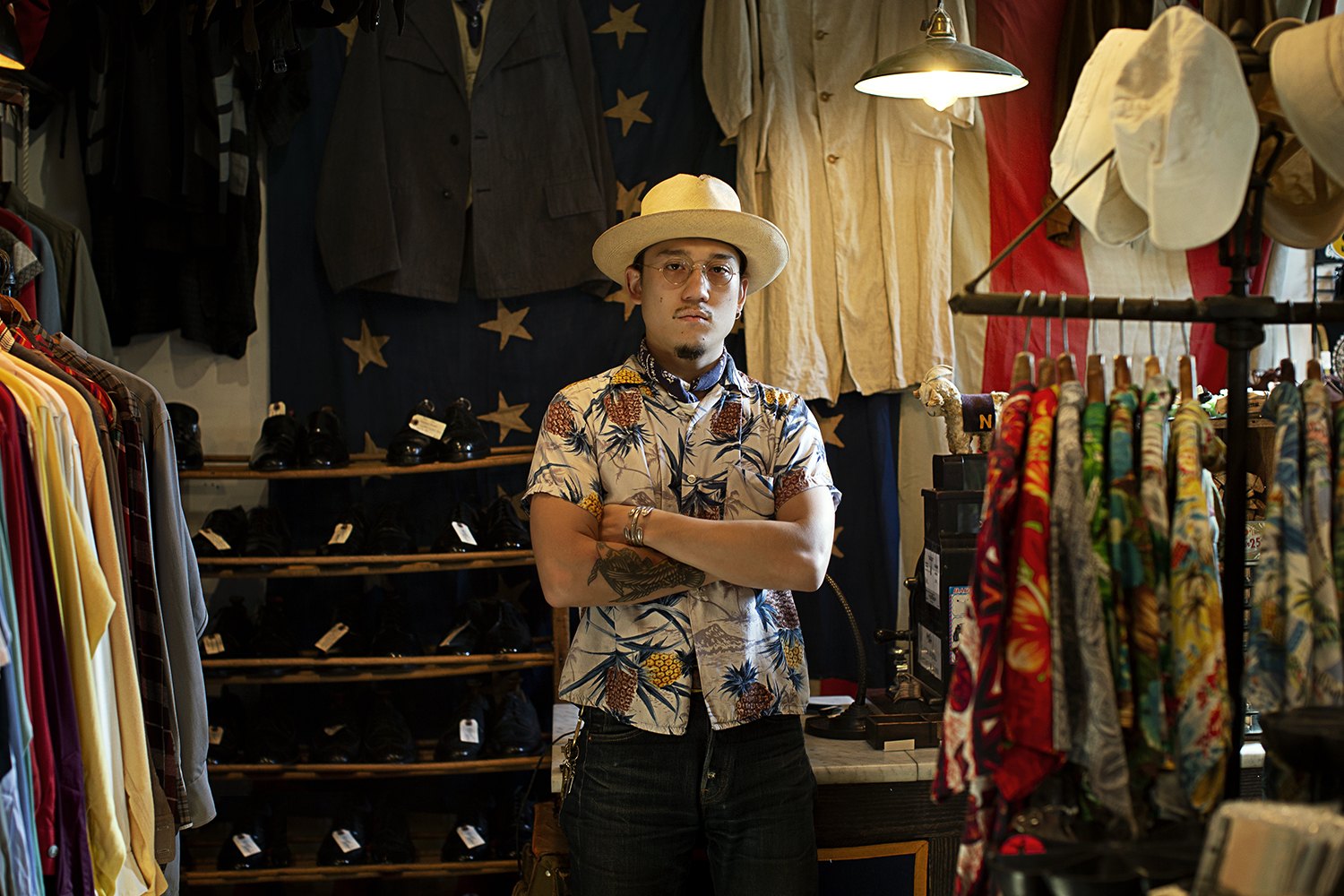 Arms folded among racks of patterned fabric and hanging shirts