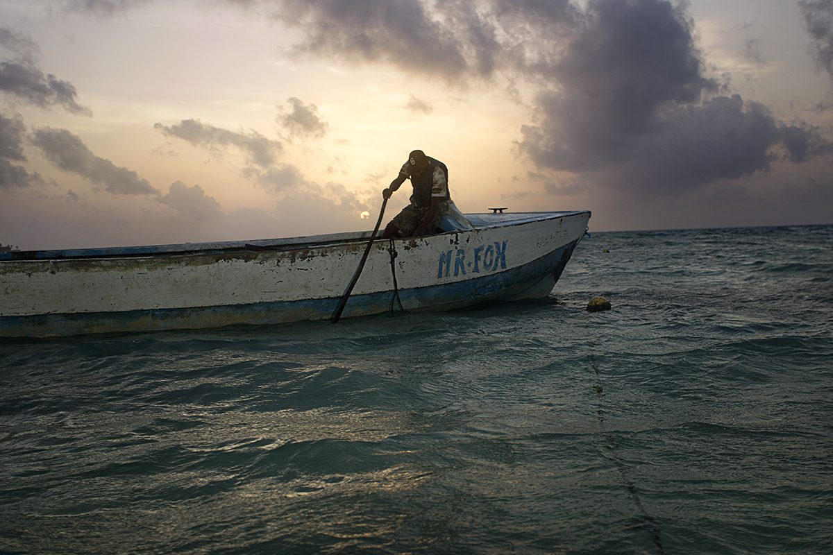 A man rows a small boat on the calm Caribbean