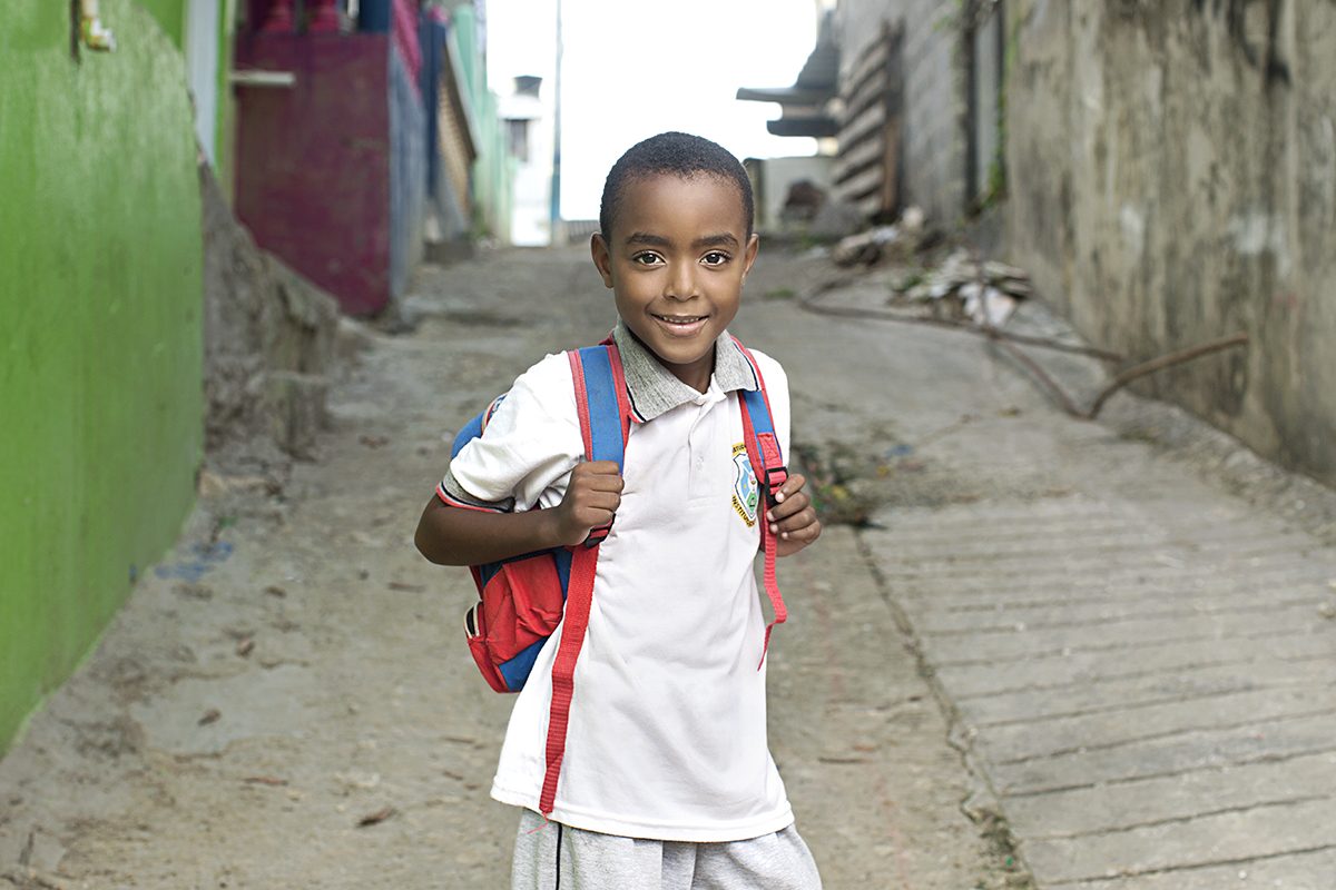 A schoolboy with a backpack in a narrow lane