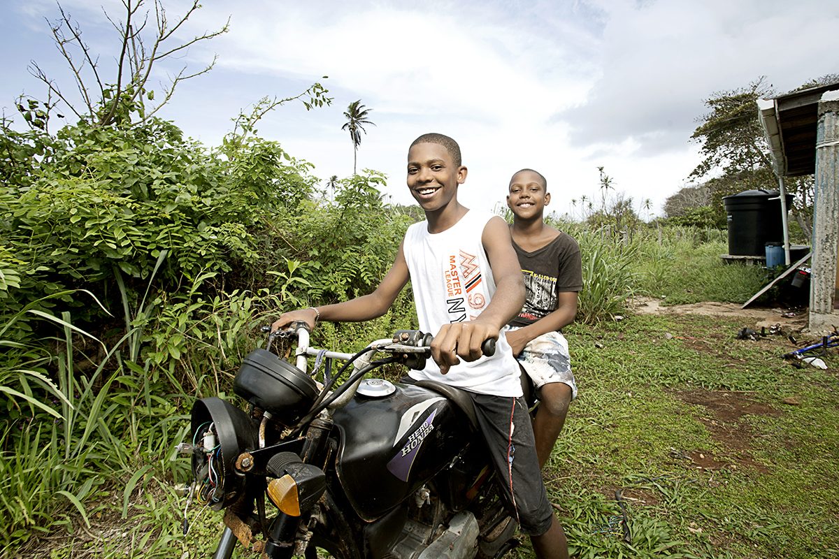 Two friends on a motorbike by the green roadside