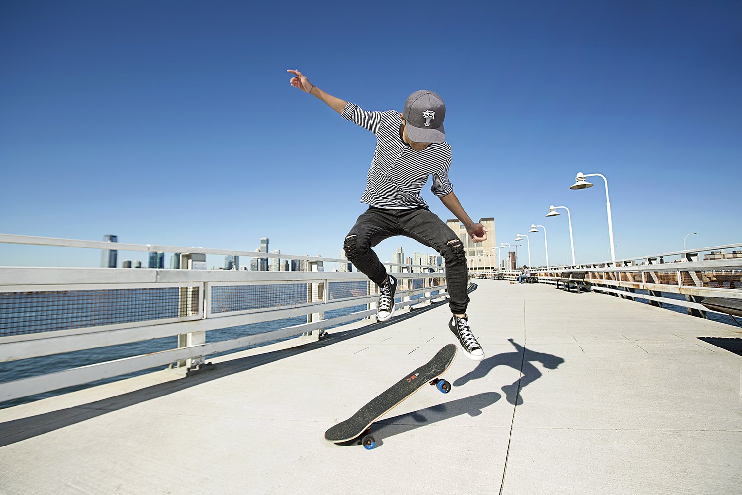 Mid-flip against a hard blue sky, board turning under his feet