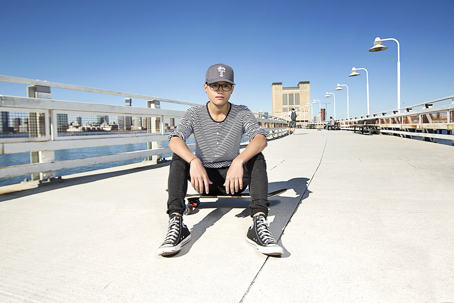 Seated on his board in the middle of the pier, skyline small on the horizon