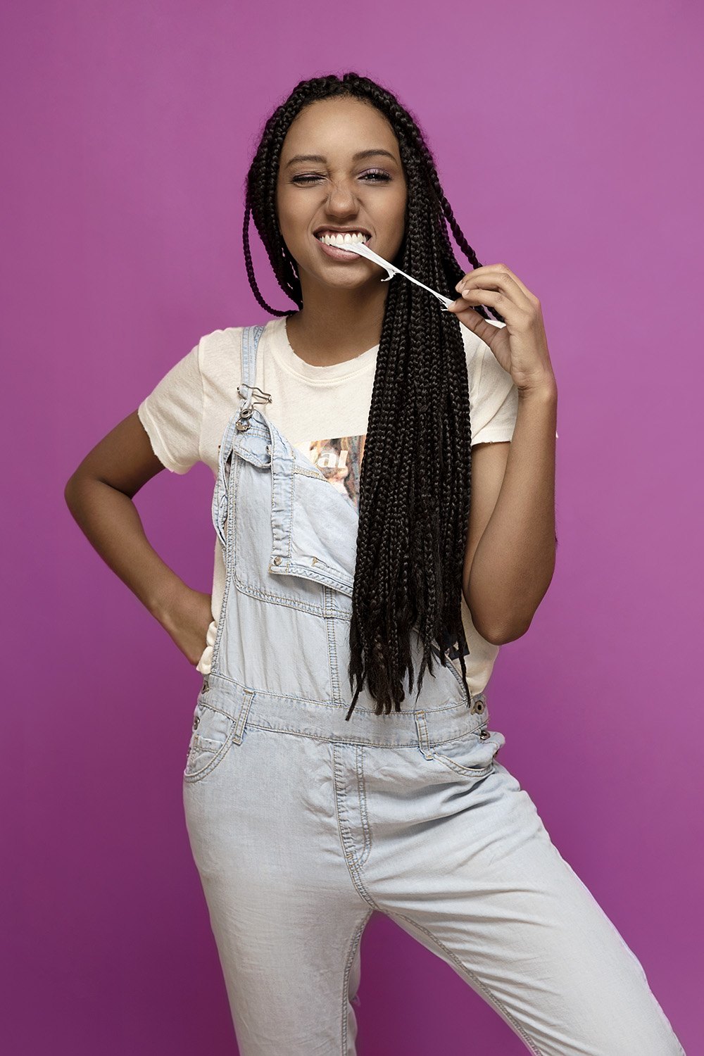 Standing in white dungarees on magenta with a lollipop