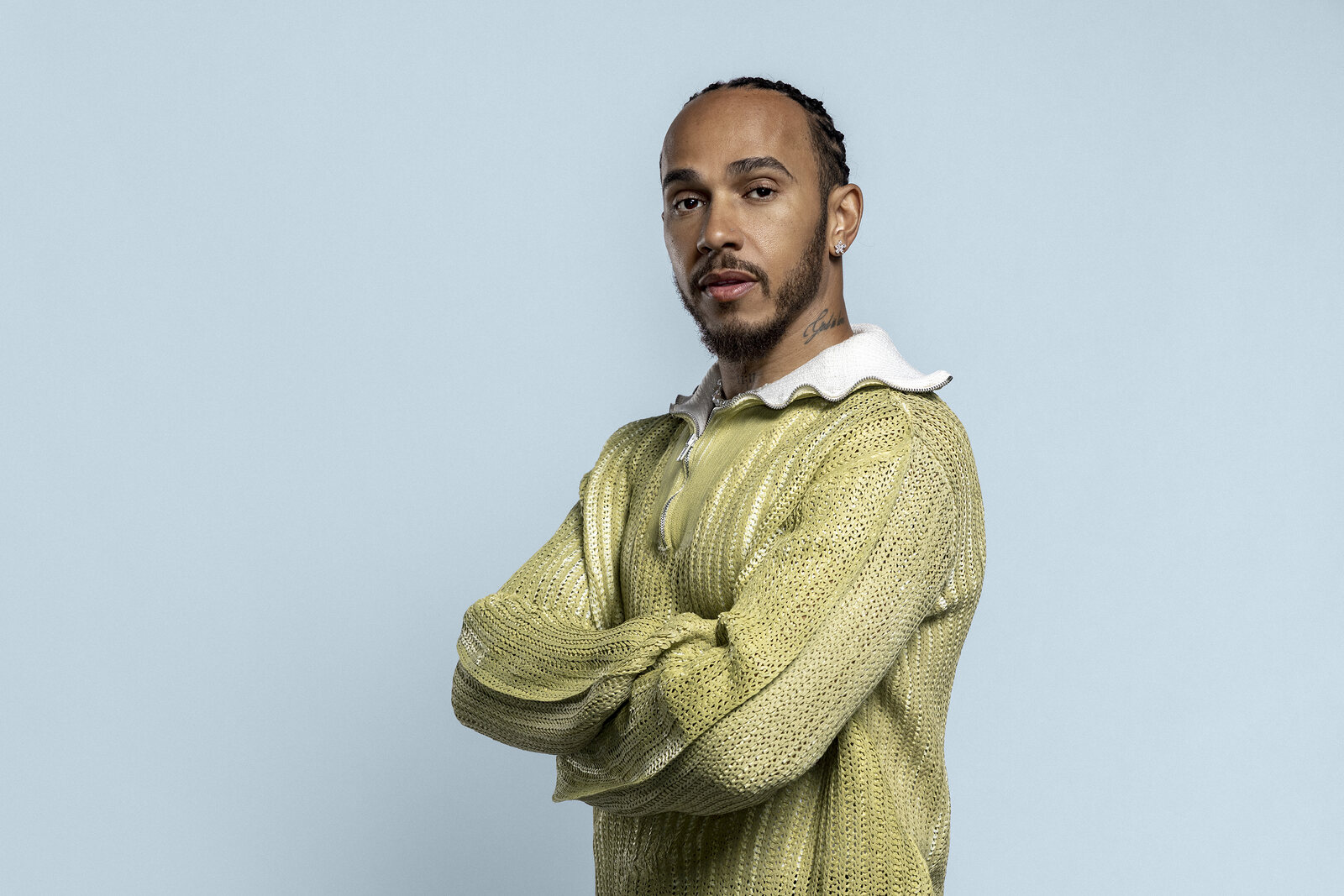 Lewis Hamilton, arms crossed in a chartreuse knit against powder blue
