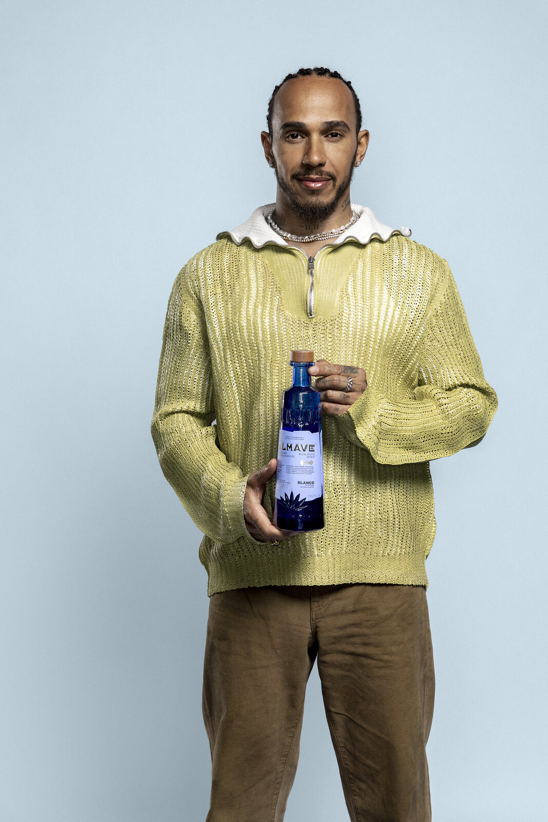Full-length portrait, the agave spirit bottle held to camera