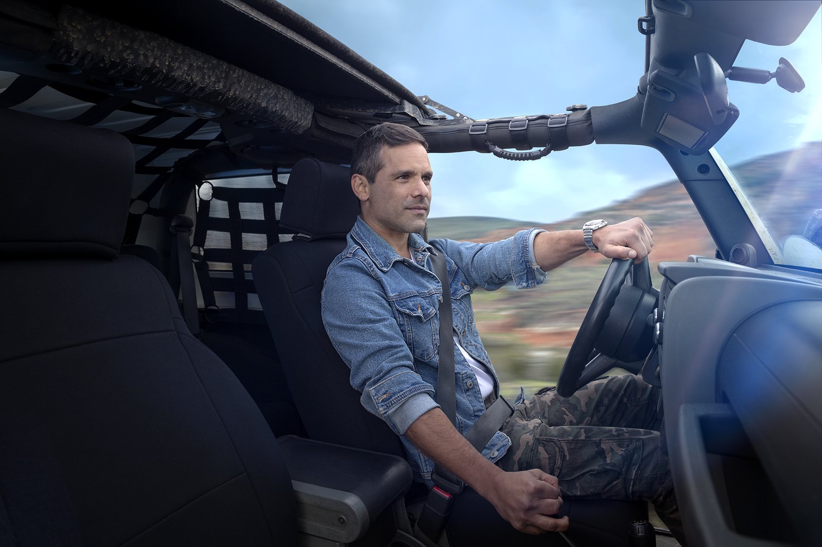 A man sitting in an open tailgate with the green valley opening out behind him