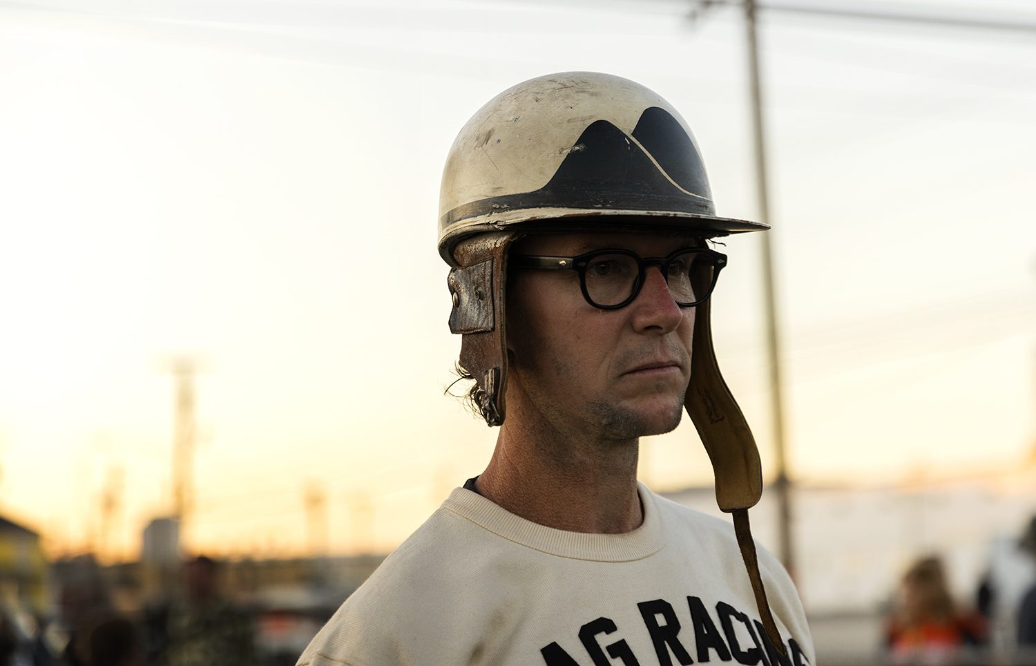 A racer in a vintage helmet and goggles at golden hour
