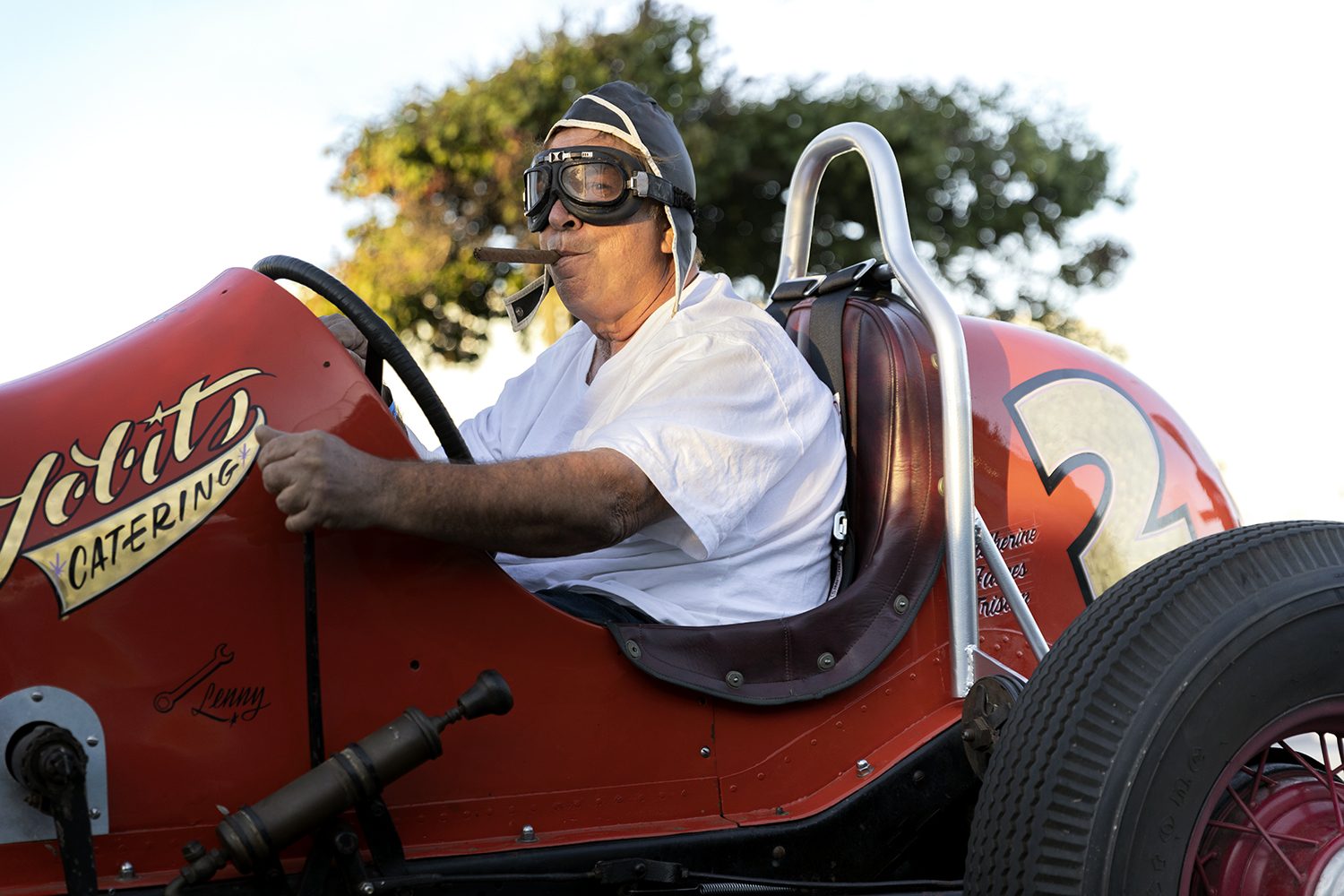 A driver at the wheel of a vintage open-wheel race car