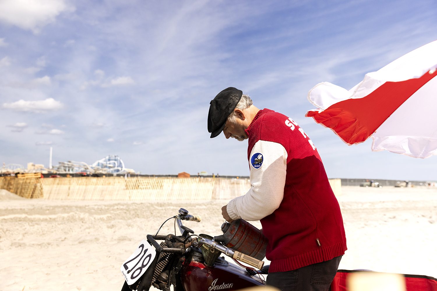 A rider in red beside a flag on the beach