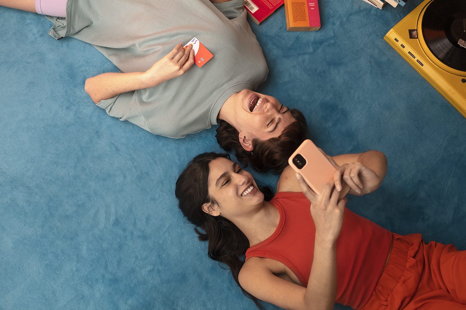 A couple lies on the floor sharing a phone, seen from above