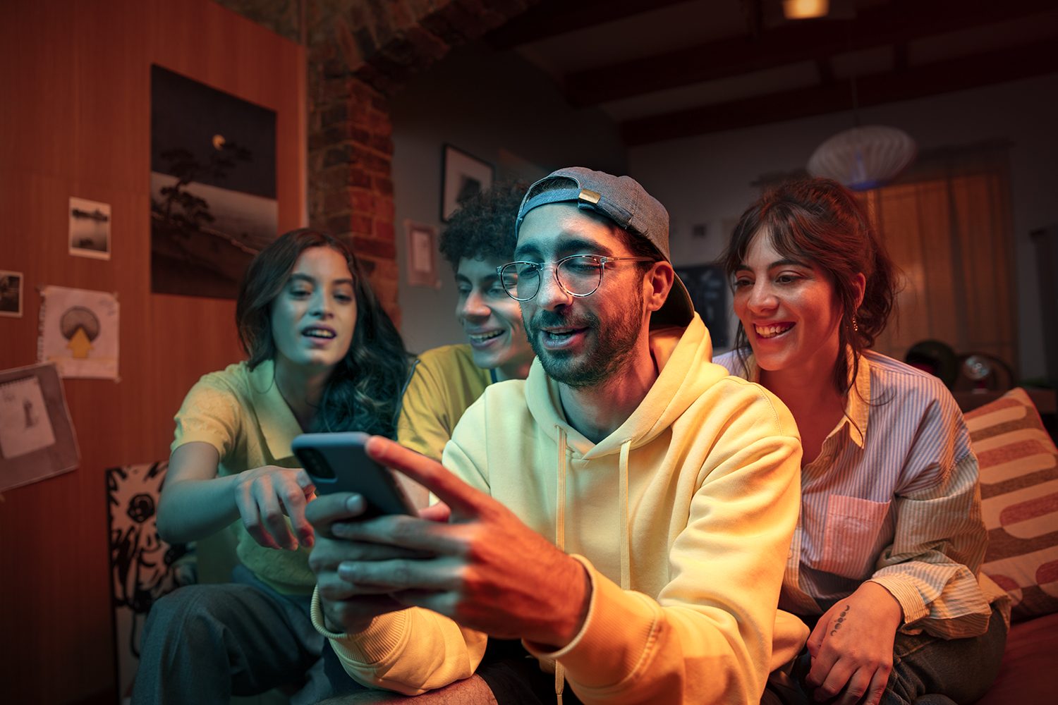 Friends laugh together over a phone on the sofa