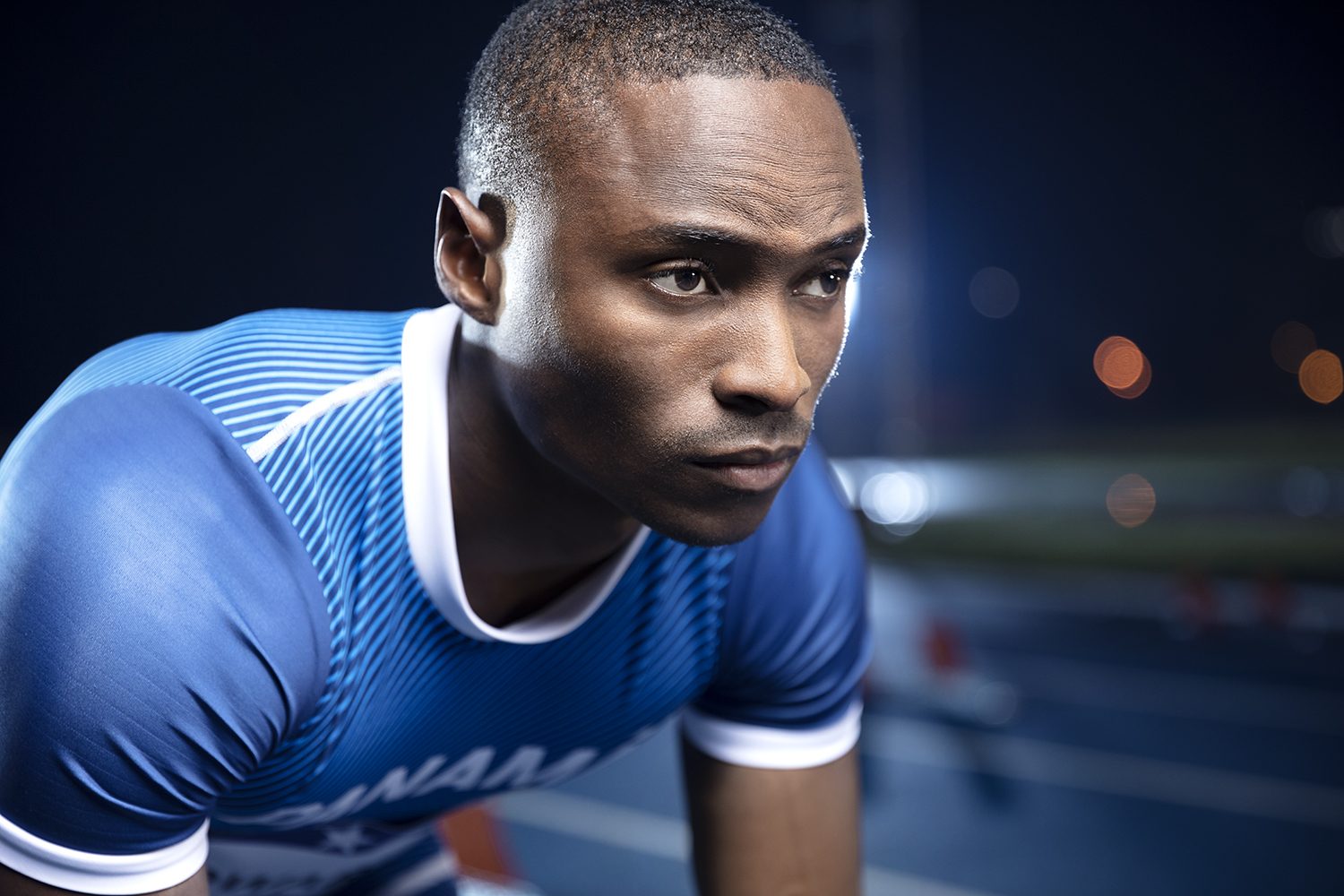 A sprinter set at the line under stadium lights