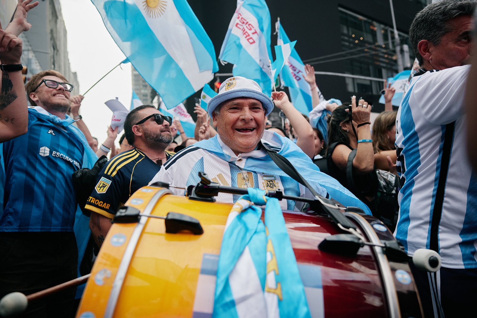 A drummer mid-beat surrounded by flags as the Argentina march moves up the avenue
