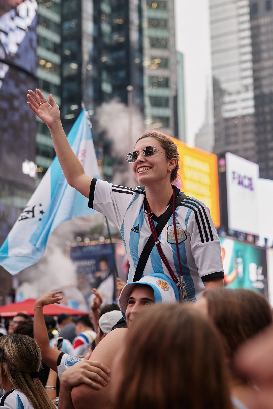 A woman in an Argentina jersey raises one arm through smoke in Times Square