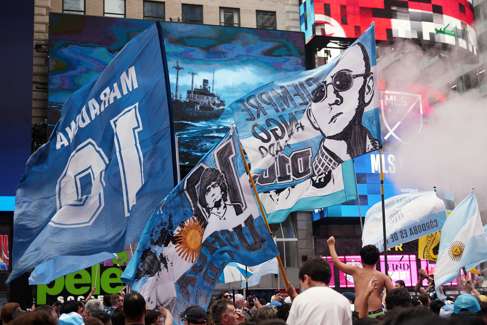 Maradona and Pele banners held aloft through red smoke as the march reaches Times Square