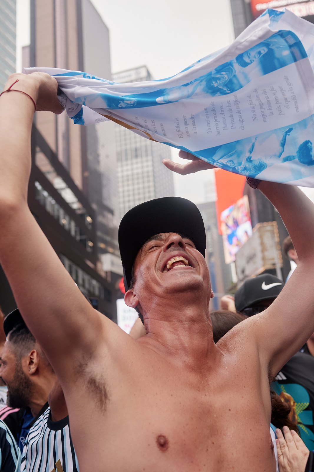 A shirtless Argentina fan holds a flag overhead and howls in the middle of a Manhattan avenue
